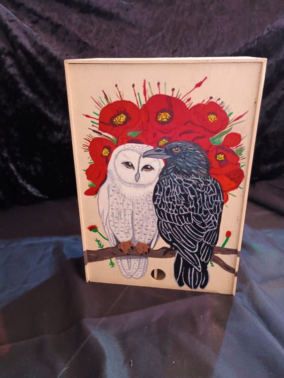 Caja con búho blanco y cuervo entre amapolas