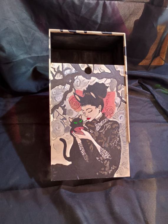 Caja con mujer y gato negro bajo un árbol