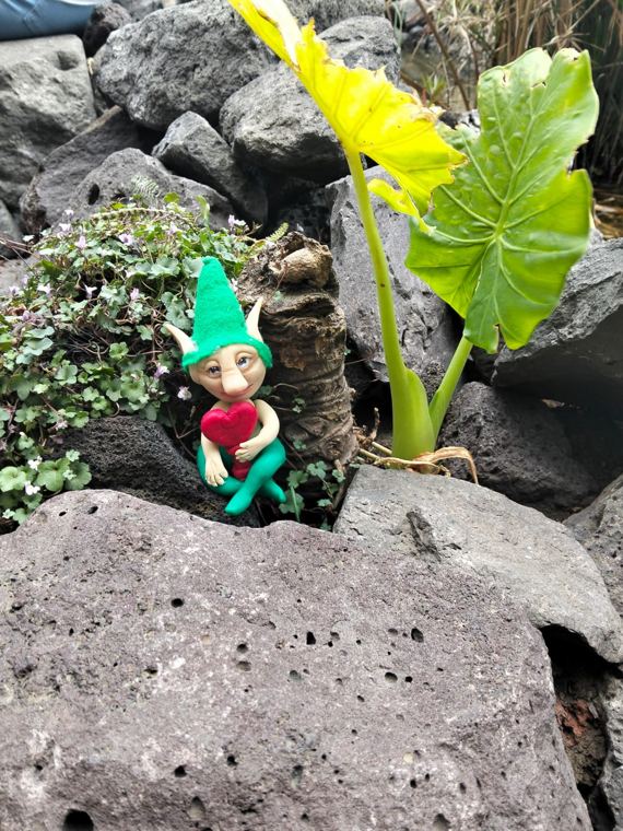 Duende de gorro verde abrazando un corazón